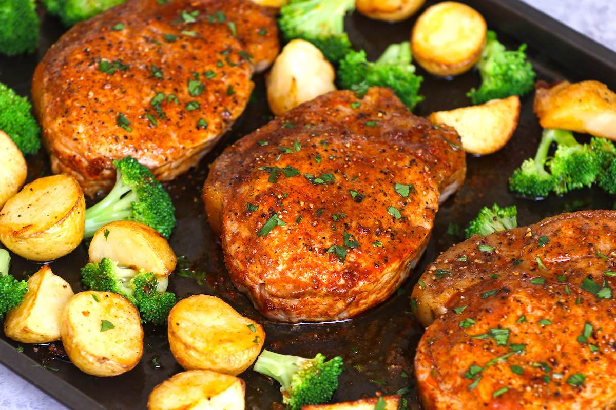 Pork chops with potatoes and broccoli on a sheet pan after baking in the oven