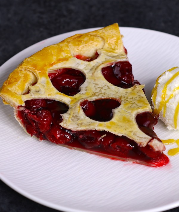 A serving of homemade cherry pie with ice cream on a plate