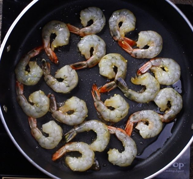 Raw shrimp in a single layer in a skillet being cooked when making a Honey Garlic Shrimp Stir Fry