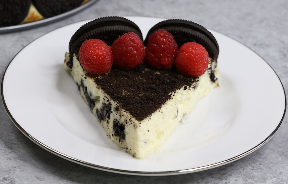 The Ultimate Oreo Cheesecake – the easiest and most beautiful cake topped with cookies and cream crumbs and fresh raspberries. All you need is a few simple ingredients: oreo cookies, cream cheese, sugar, vanilla, eggs, sour cream and raspberries. Great for dessert, brunch, birthday parties or Mother’s Day. Video recipe. | tipbuzz.com